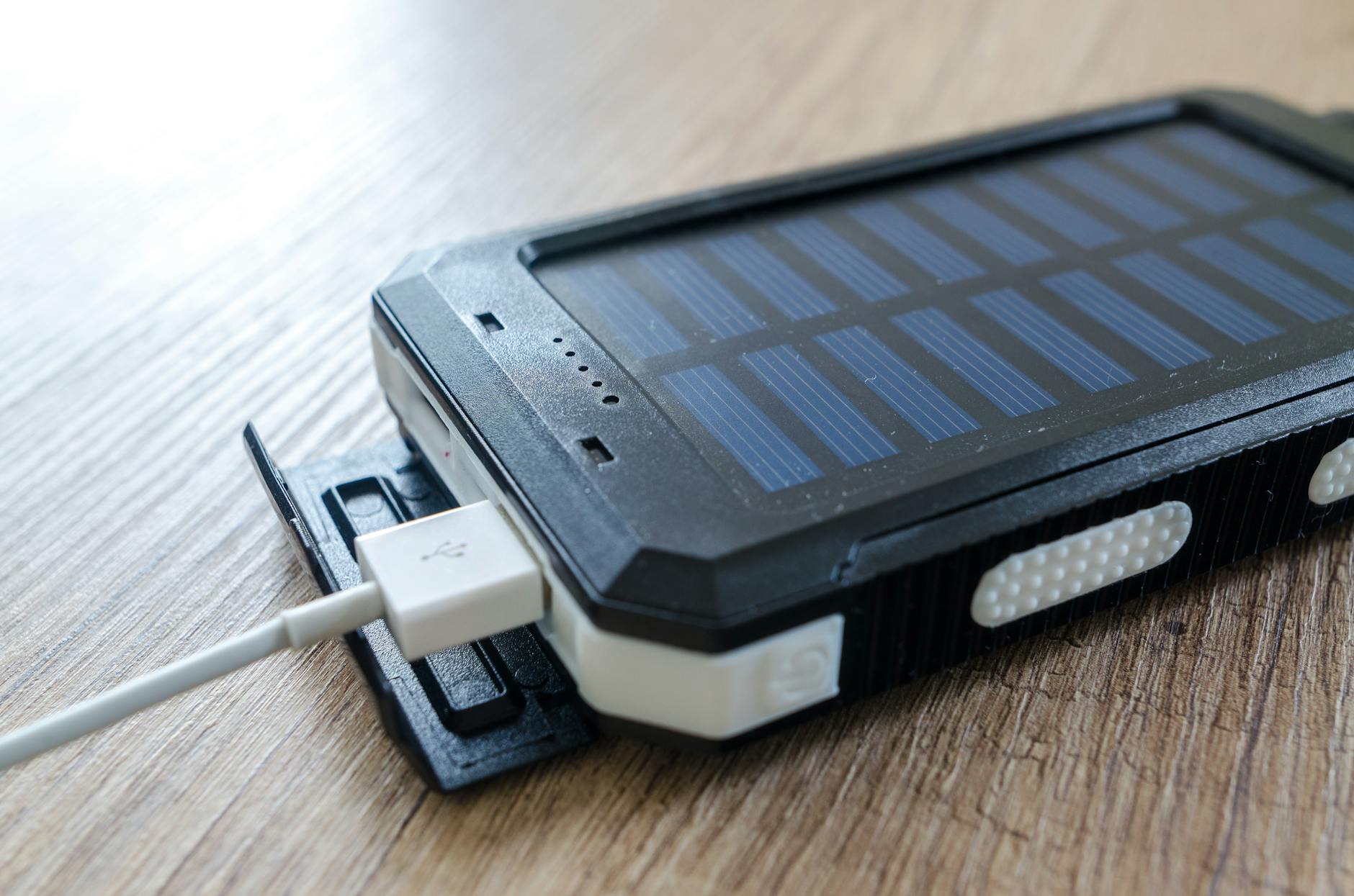 Zbliżenie na solarną ładowarkę USB leżącą na drewnianym blacie