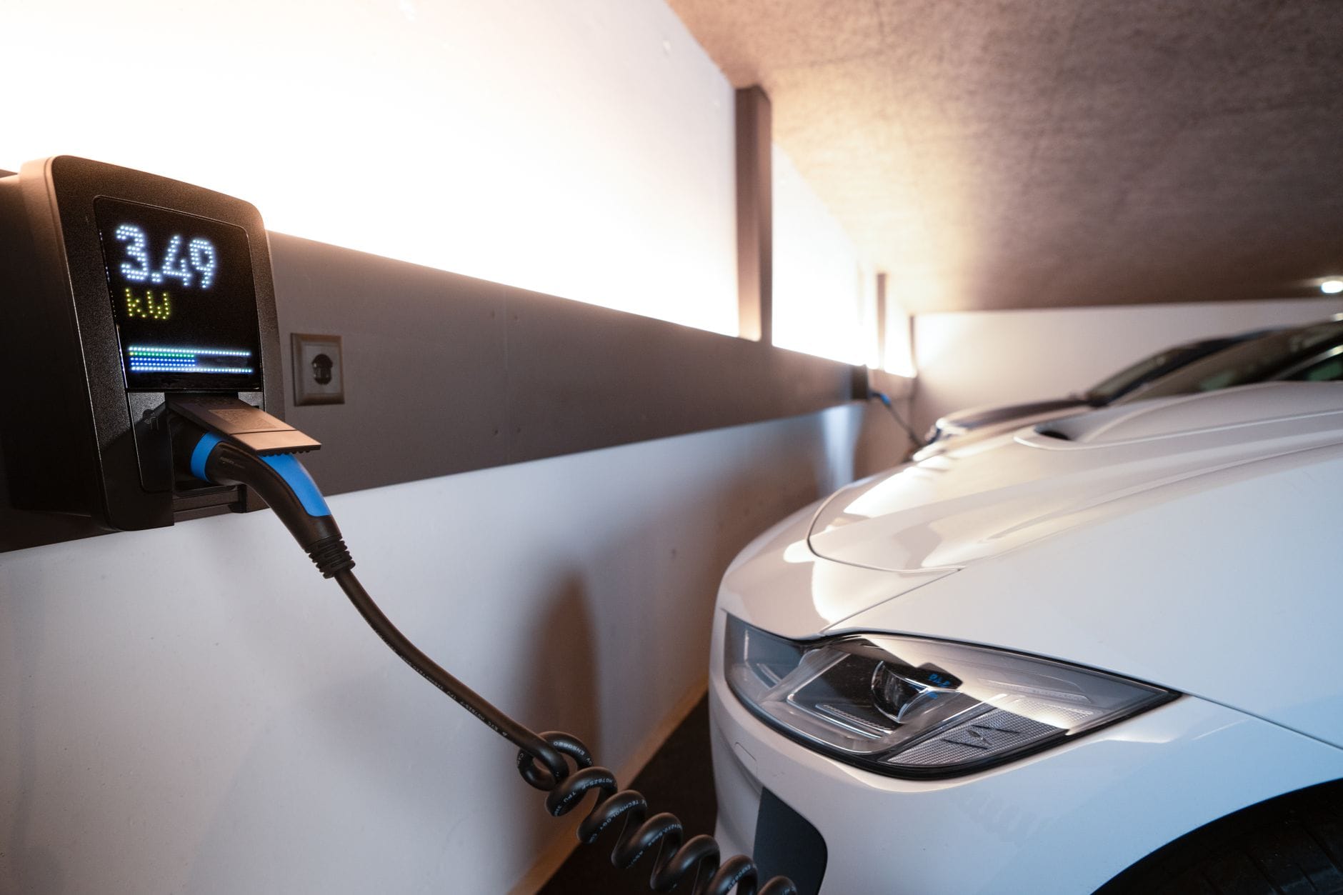 Biały samochód elektryczny ładowany na wewnętrznej stacji